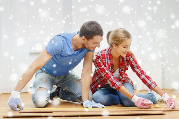 Coppia sorridente misurazione pavimenti in legno — Foto Stock