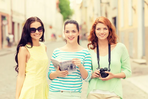 Lachende tienermeisjes met city guide en camera — Stockfoto