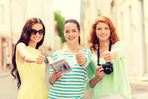 Lachende tienermeisjes met city guide en camera — Stockfoto