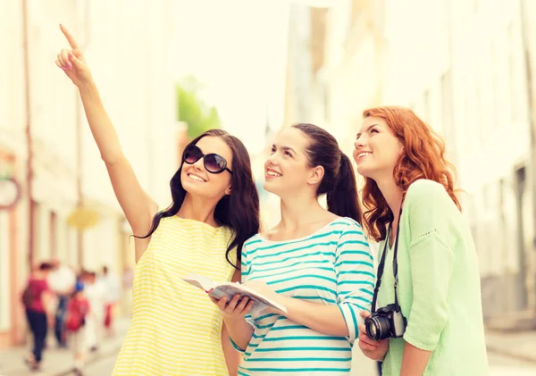 Lachende tienermeisjes met city guide en camera — Stockfoto