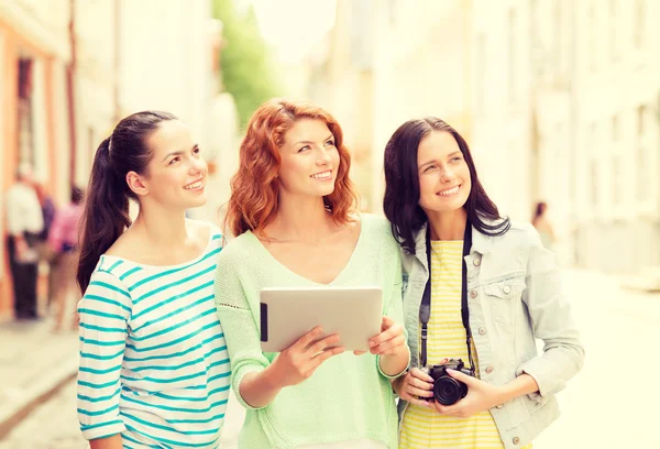 Lachende tienermeisjes met tablet pc en camera — Stockfoto