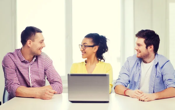 Trois collègues souriants avec ordinateur portable au bureau — Photo