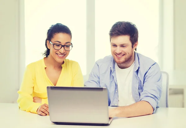 Deux personnes souriantes avec ordinateur portable au bureau Photos De Stock Libres De Droits