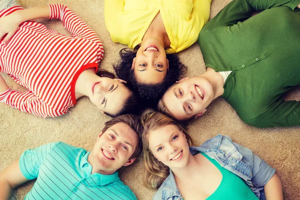 Group of smiling people lying down on floor — Stock Photo, Image