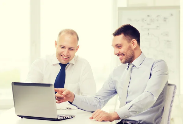 Two smiling businessmen with laptop in office — Stock Photo, Image