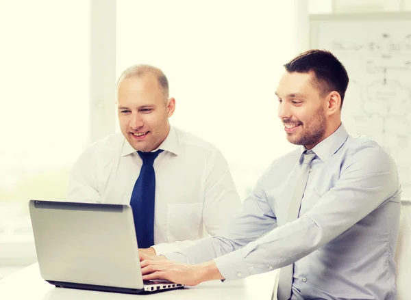 Two smiling businessmen with laptop in office — Stock Photo, Image