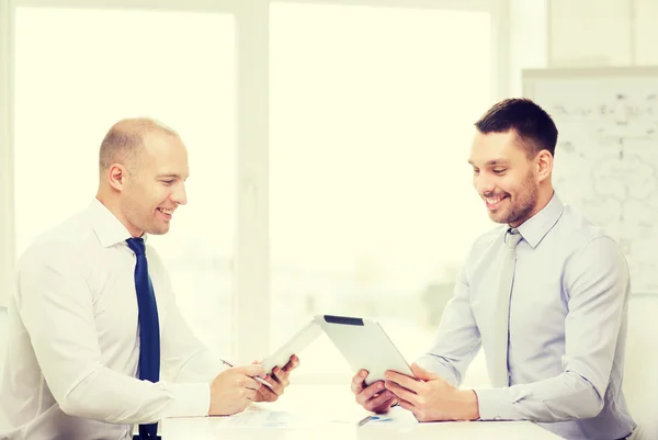 Два улыбающихся бизнесмена с планшетным ПК в офисе — стоковое фото