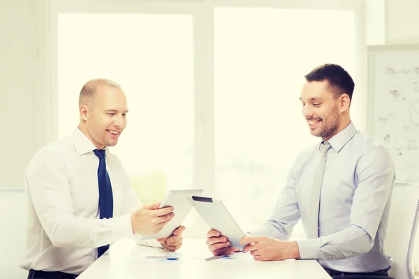 Два улыбающихся бизнесмена с планшетным ПК в офисе — стоковое фото