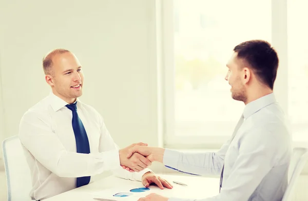 Dos hombres de negocios sonrientes estrechando la mano en la oficina —  Fotos de Stock