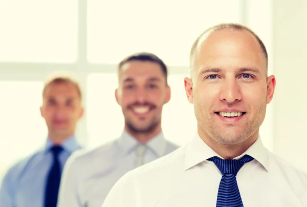 Lächelnder Geschäftsmann im Amt mit Team auf dem Rücken — Stockfoto