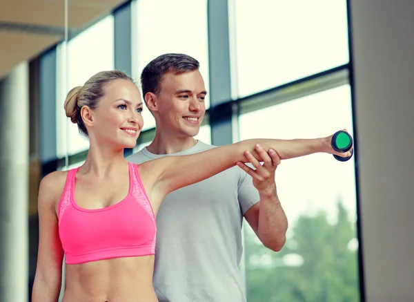 Spor salonunda kişisel antrenörüyle gülümseyen genç bir kadın. — Stok fotoğraf