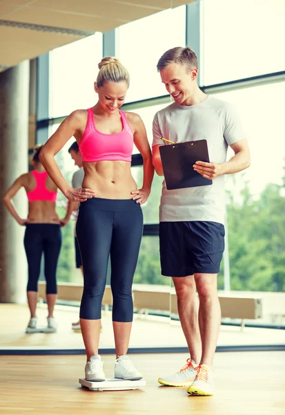 Smiling man and woman with scales in gym — Stock Photo, Image