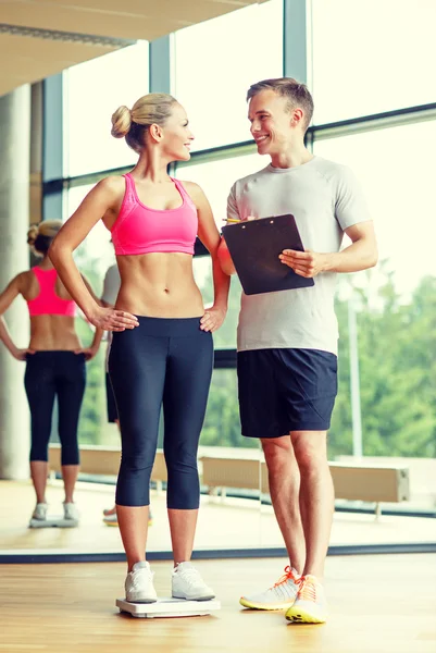 Smiling man and woman with scales in gym — Stock Photo, Image