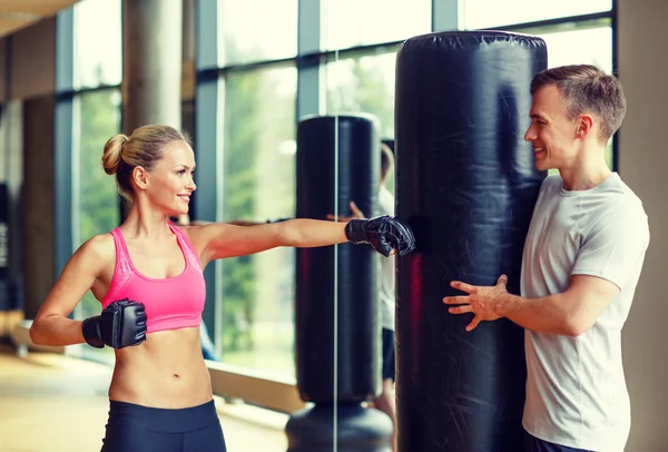 Smiling woman with personal trainer boxing in gym — Stock Photo, Image