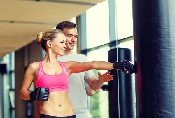 Lächelnde Frau mit Personal Trainer beim Boxen im Fitnessstudio — Stockfoto