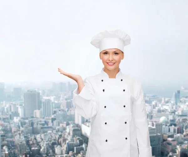 Smiling female chef holding something on hand — Stock Photo, Image