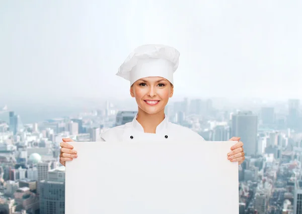 Smiling female chef with white blank board — Stock fotografie