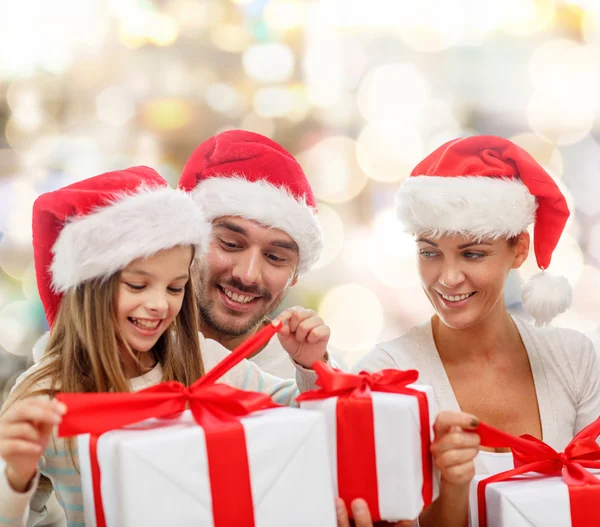 Familia feliz en sombreros de santa sentado con cajas de regalo —  Fotos de Stock