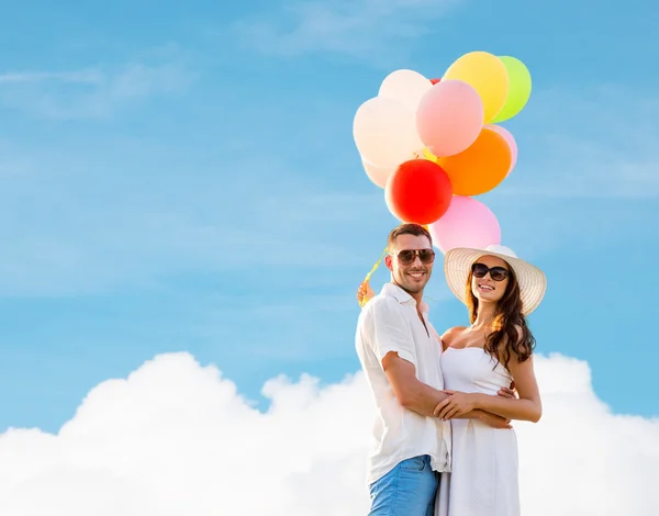 Smiling couple with air balloons outdoors — Stock Photo, Image