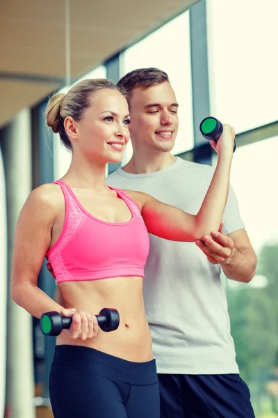 Smiling young woman with personal trainer in gym Royalty Free Stock Images