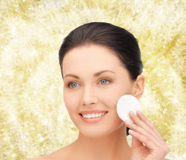 Mulher sorridente limpeza rosto pele com almofada de algodão Imagens Royalty-Free