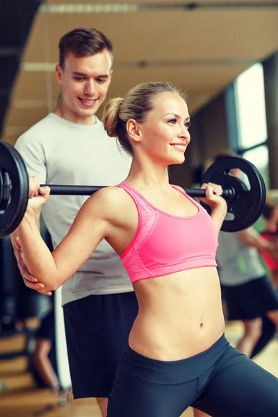 Glimlachende man en vrouw met barbell in gym — Stockfoto