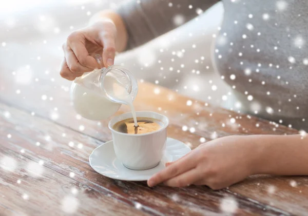 Закрыть женский налив молока в чашку кофе — стоковое фото