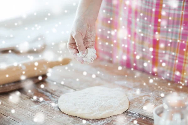 Close up of woman hand sprinkling dough with flour — Stock Photo, Image