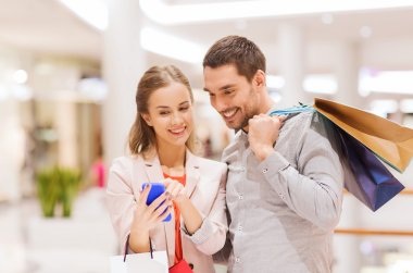 couple with smartphone and shopping bags in mall clipart
