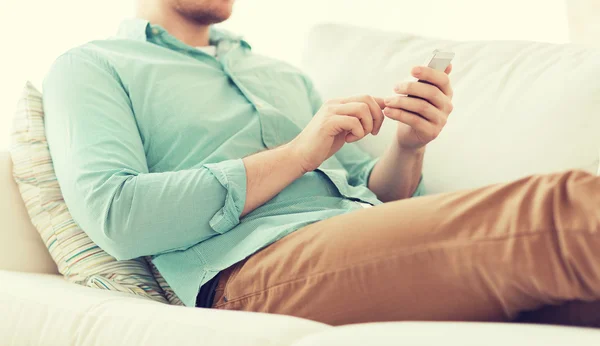 Nahaufnahme eines Mannes, der mit Smartphone zu Hause sitzt — Stockfoto