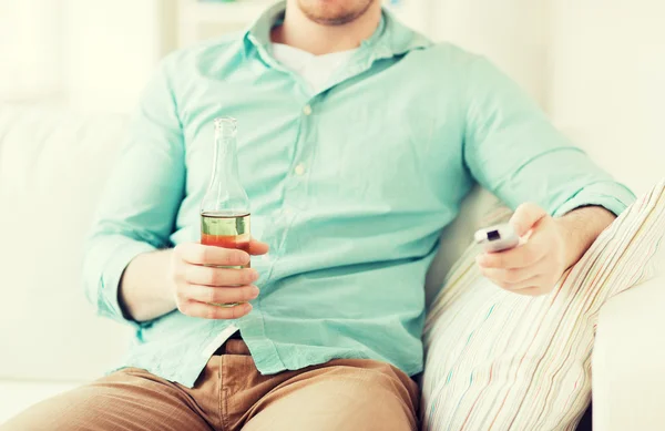 Man with beer and remote control at home — Stock Photo, Image