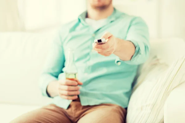 Hombre con cerveza y control remoto en casa — Foto de Stock