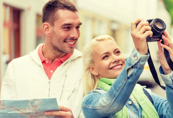 Usmívající se pár s mapou a fotokamery v městě — Stock fotografie