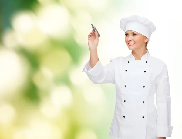 Smiling female chef writing something on air — Stock Photo, Image