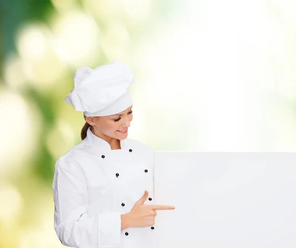 Smiling female chef with white blank board — Stock fotografie