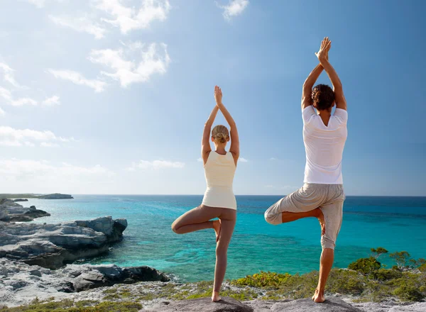 Coppia fare esercizi di yoga sulla spiaggia da dietro — Foto Stock