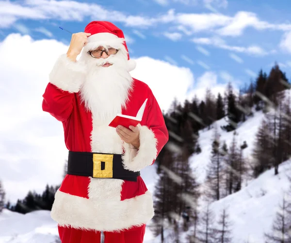 Homem em traje de santa claus com bloco de notas — Fotografia de Stock