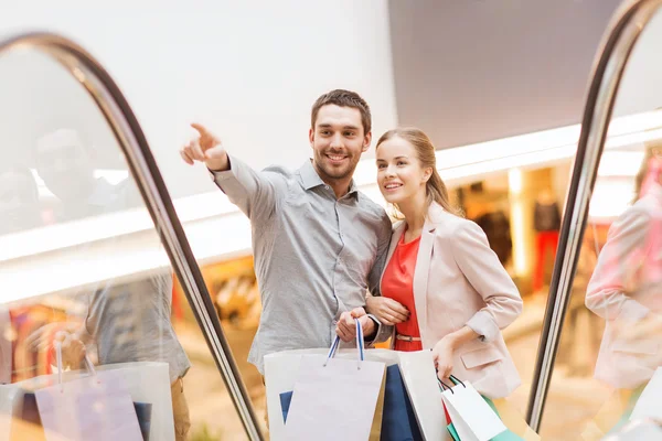 Lyckligt ungt par med shoppingväskor i köpcentret — Stockfoto