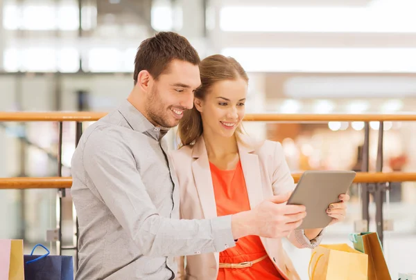 Casal com tablet pc e sacos de compras no shopping — Fotografia de Stock