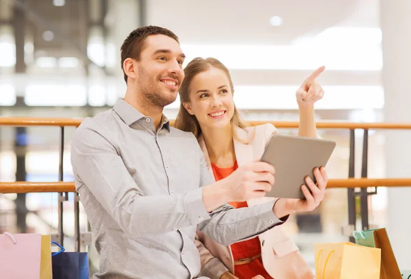 Pareja con tablet pc y bolsas de compras en el centro comercial —  Fotos de Stock