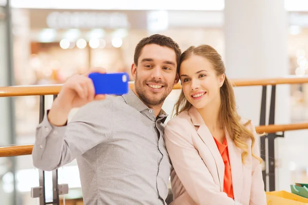 Gelukkige paar met smartphone nemen selfie in winkelcentrum — Stockfoto