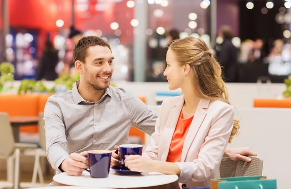 Gelukkige paar met boodschappentassen drinken koffie — Stockfoto