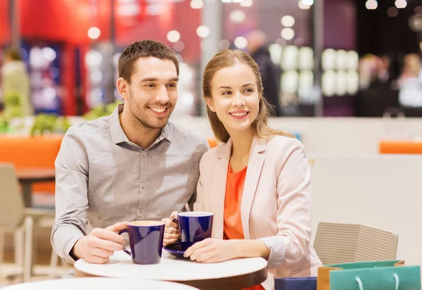 Feliz pareja con bolsas de compras beber café —  Fotos de Stock