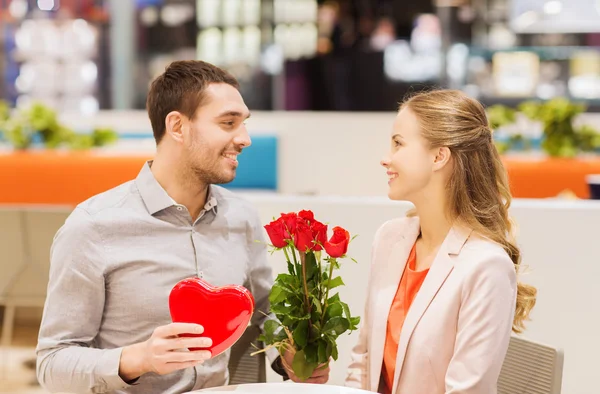 Lyckliga par med present och blommor i gallerian — Stockfoto