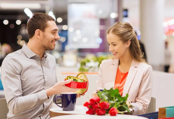 Casal feliz com presente e flores no shopping — Fotografia de Stock