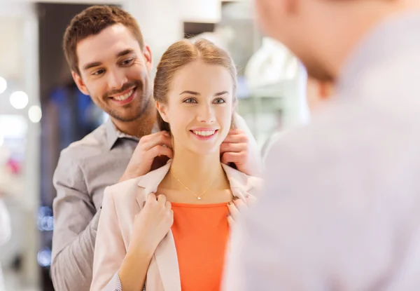 Couple trying golden pendant on at jewelry store — Stock Photo, Image