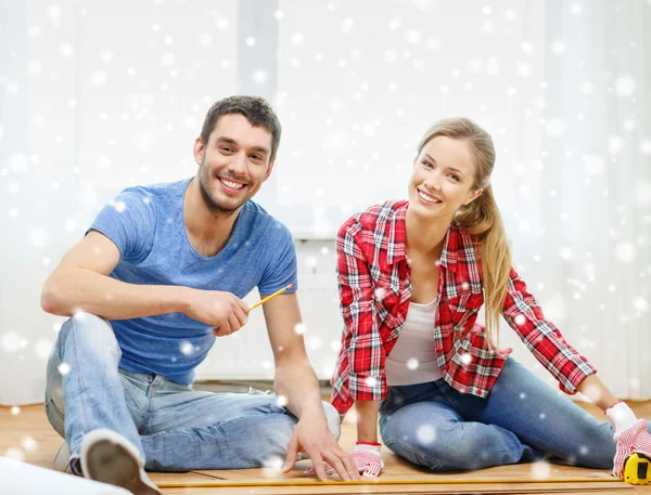 Casal sorridente medindo piso de madeira — Fotografia de Stock