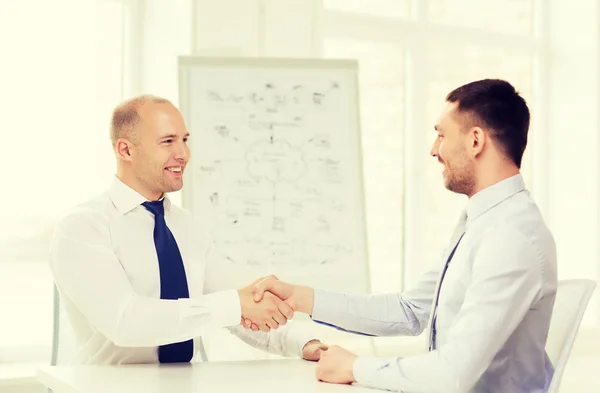 Twee Glimlachende zakenmensen schudden handen in office — Stockfoto