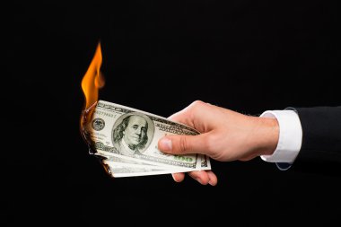close up of male hand holding burning dollar money clipart