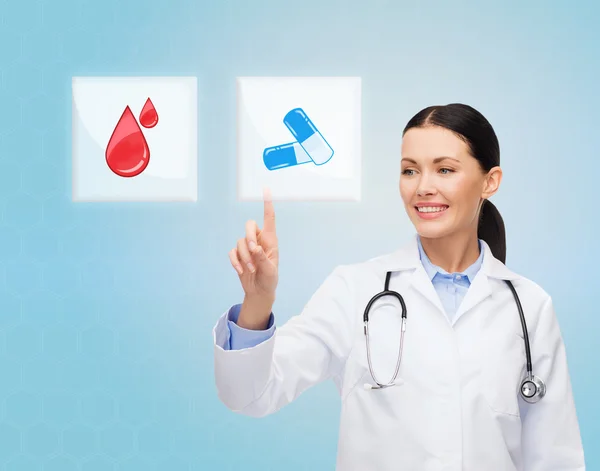 Smiling doctor or nurse pointing to pills icon — Stock Photo, Image